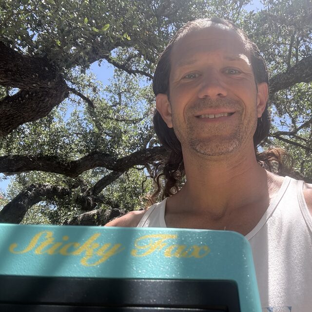 Dan, grinning under a Texas live oak, holding a StickyFax
