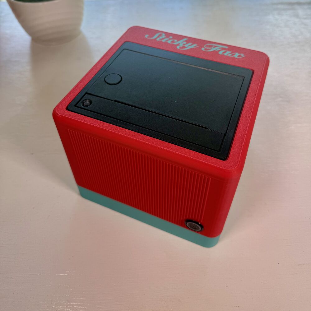 A signal-red-and-teal-green StickyFax on a desk