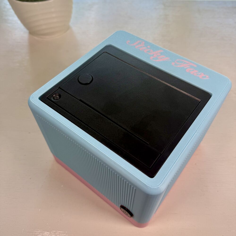 A powder-blue-and-petal-pink StickyFax on a desk